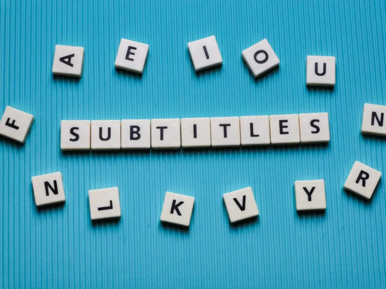 Les jetons de scrabble qui forment le mot ''sous-titres'' avec d'autres jetons éparpillés autour sur un fond bleu clair. L'image symbolise la traduction audiovisuelle.